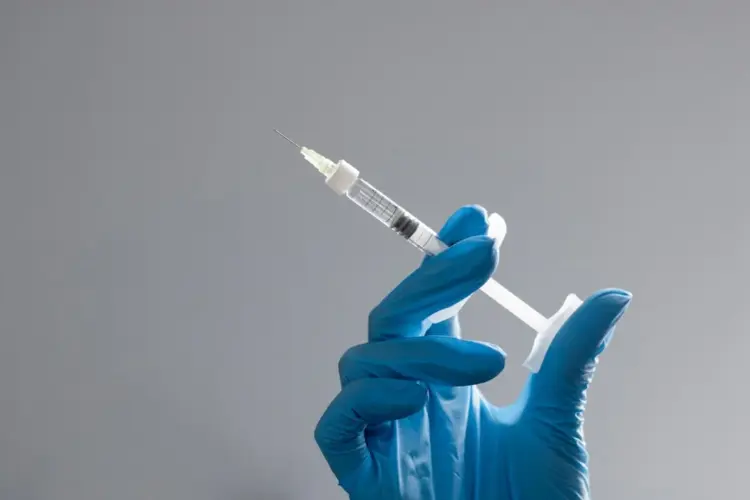 Gloved hand holding a syringe — illustrating peptide injection therapy